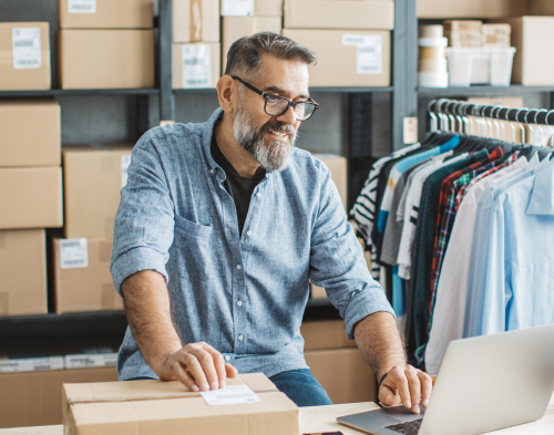 small business owner older man printing shipping labels from laptop