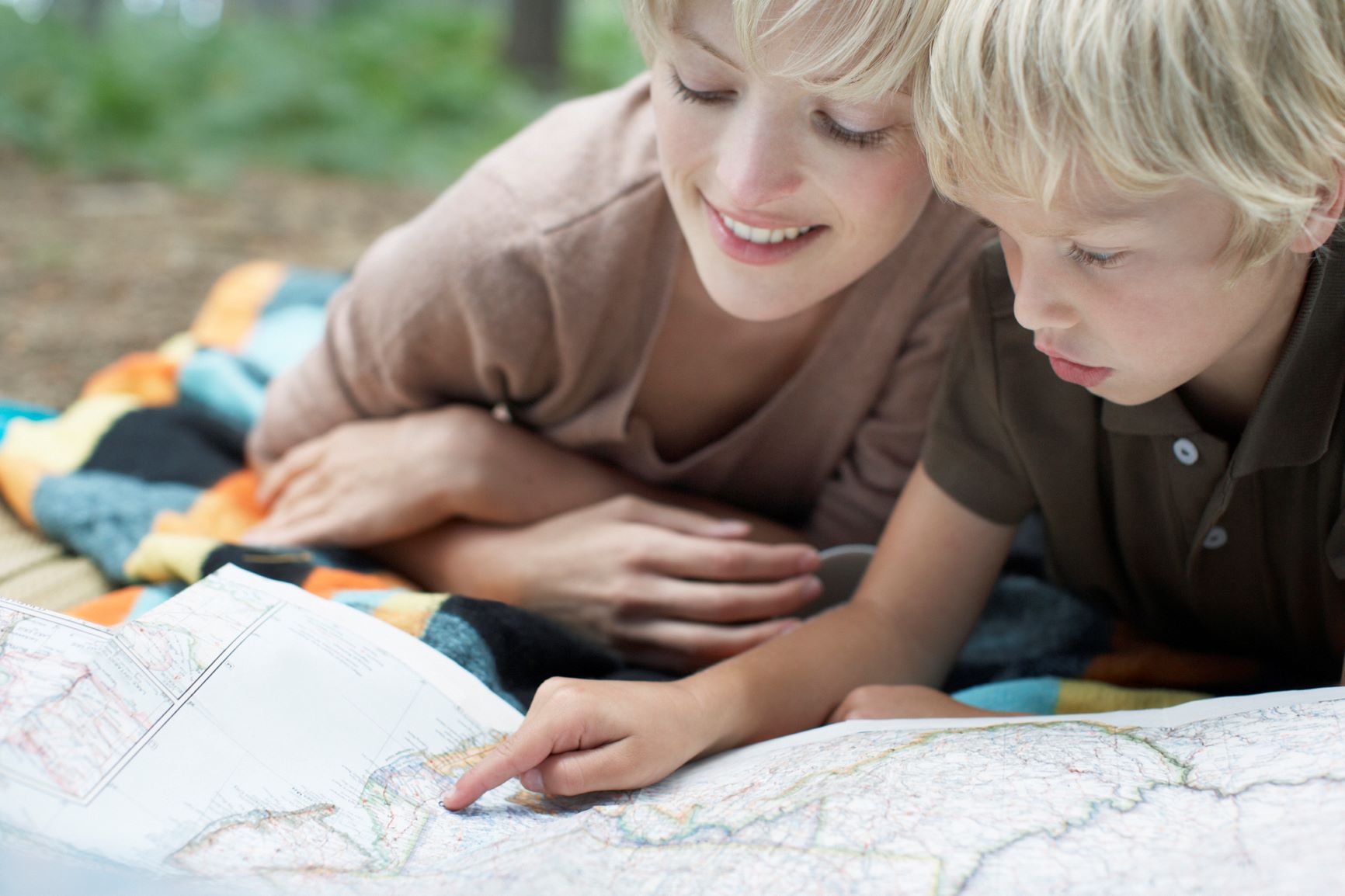 caucasian woman with young son smiling, looking at a map while travelling