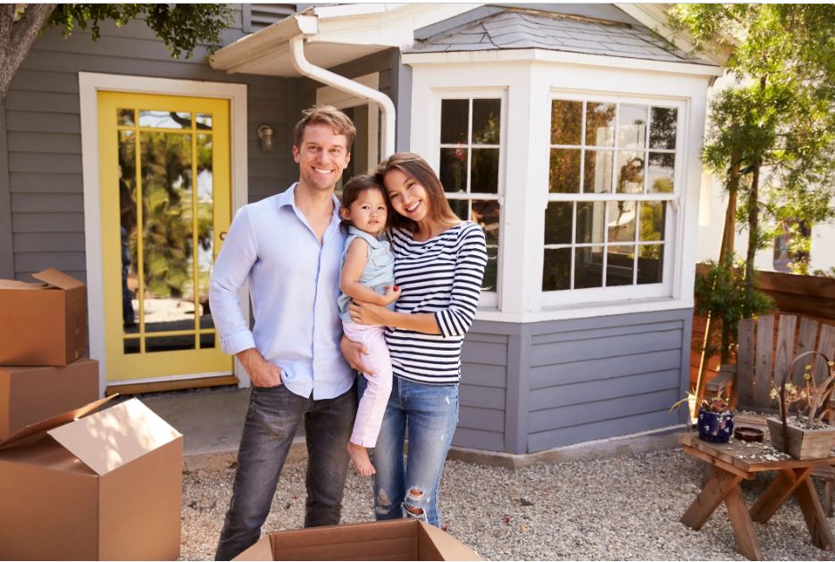 Portrait Of Excited Family Standing Outside New Home