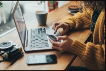 Woman typing on laptop with credit card in hand