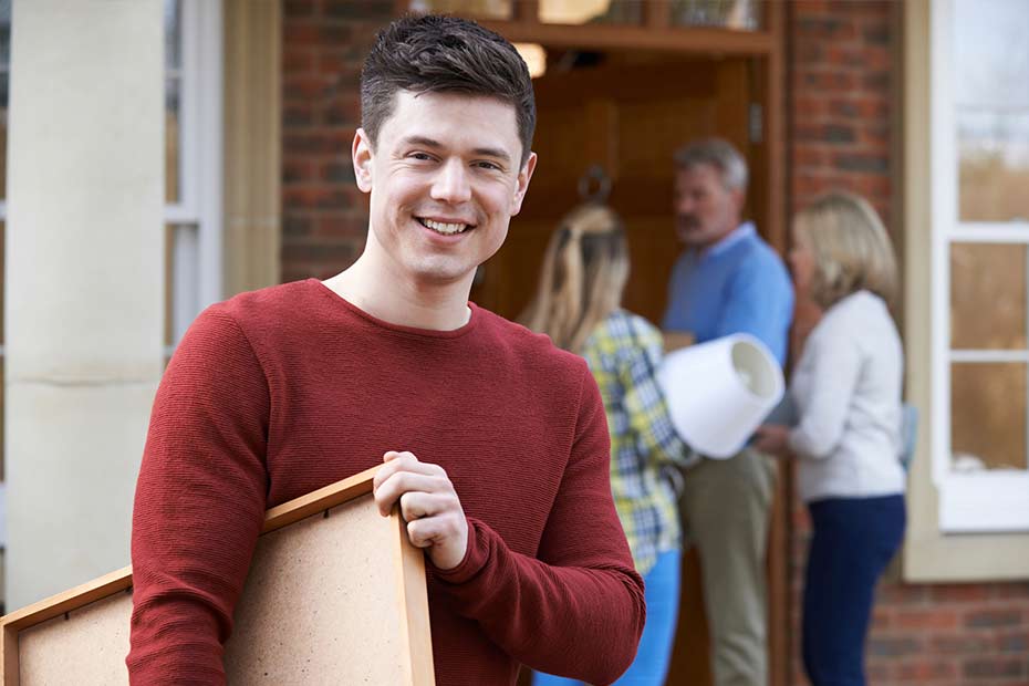 A male college student smiling with his parents helping him move