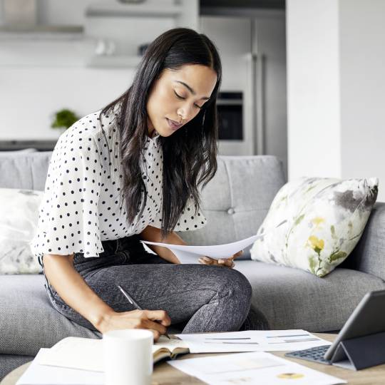 Young woman analyzing bills while writing in diary.