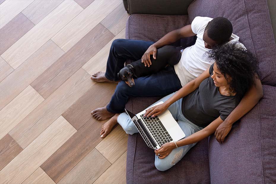 Top view of happy young couple online shopping sitting on sofa with pet