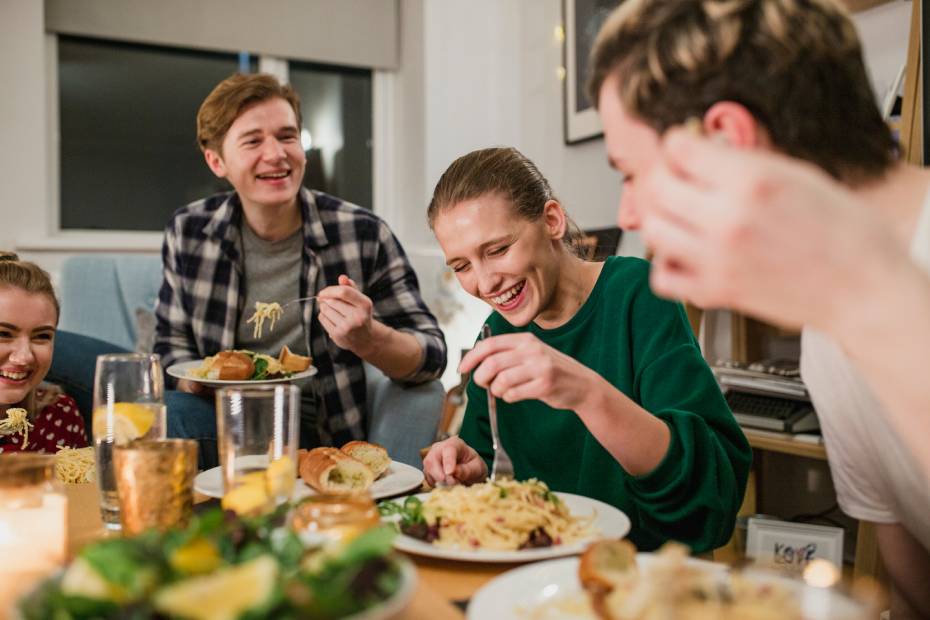 A group of people sit around a dining table and enjoy a shared meal at home together