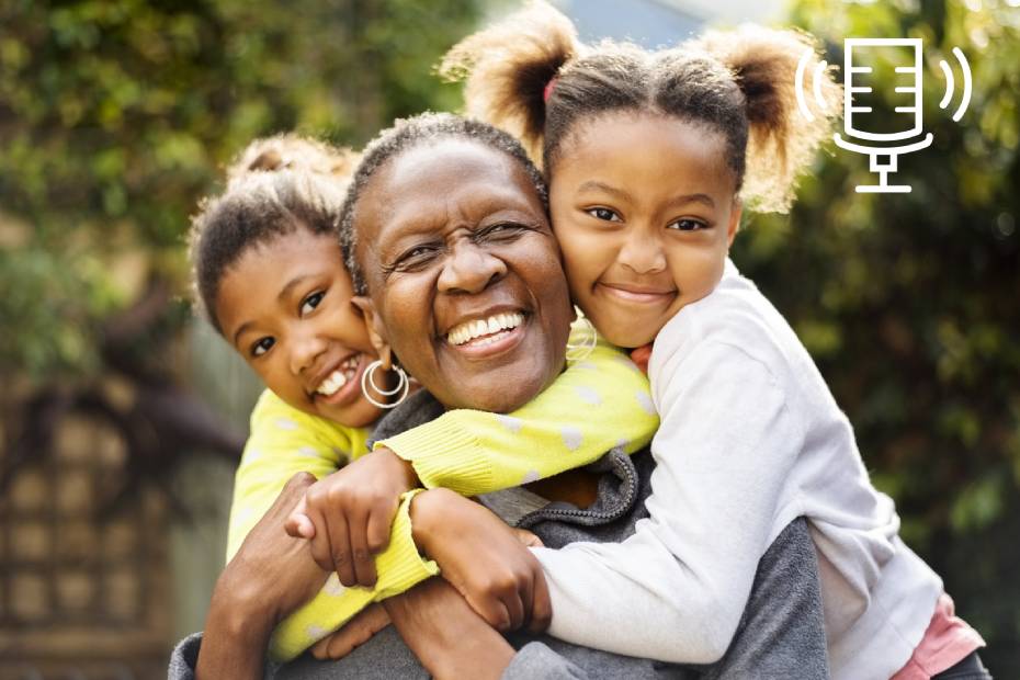 A grandmother smiles while being hugged by her two granddaughters