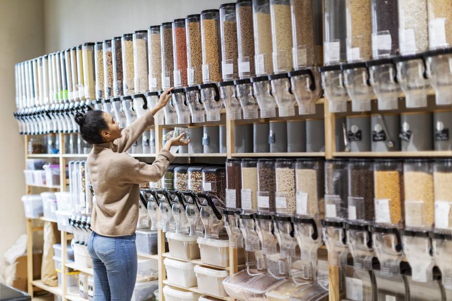 A young female customer filled a container with dried beans in a co-op.