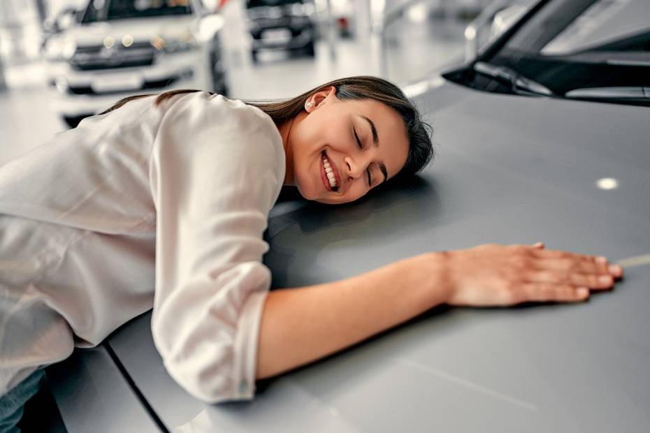 Young car buyer enjoying her new car in a car showroom.