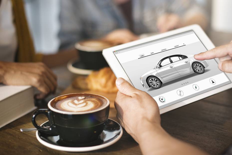 A person looks at electric vehicles on their tablet in a coffee shop.