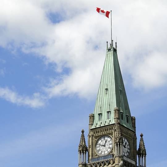 A Canadian flag flies above the main building of the Canadian parliamentary complex on Parliament Hill.