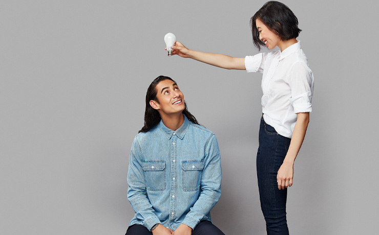 A lady holding a lightbulb above a mans head