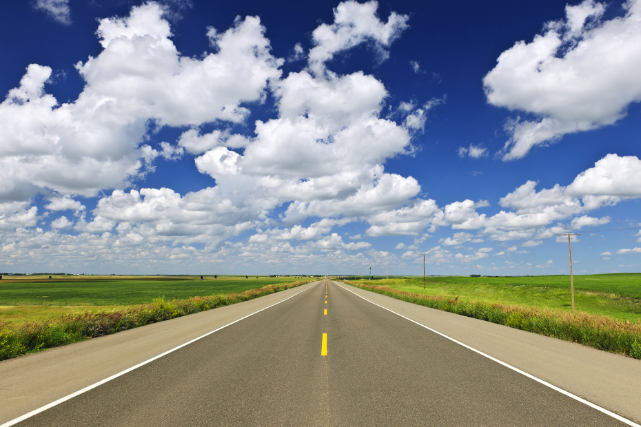 A landscape view of the open road leading to the horizon, with blue skies.