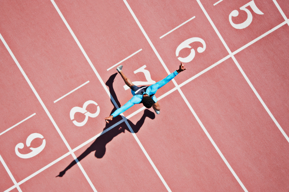 A runner crosses a finish line in a concept for achieving investing milestones.