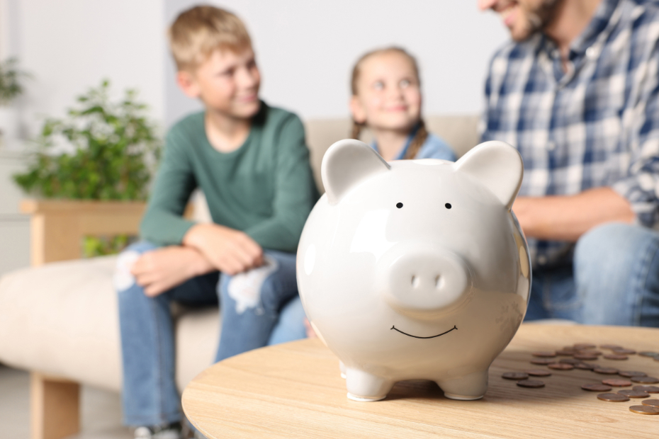 A father with his son & daughter with a piggy bank in focus in the foreground