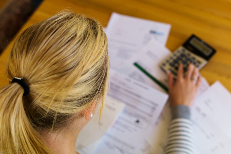 From behind image of a woman sitting at a desk going over expenses