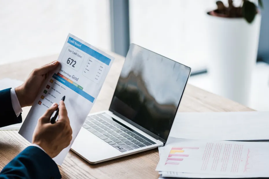 A man with a printed copy of his credit report, reviewing finances online.