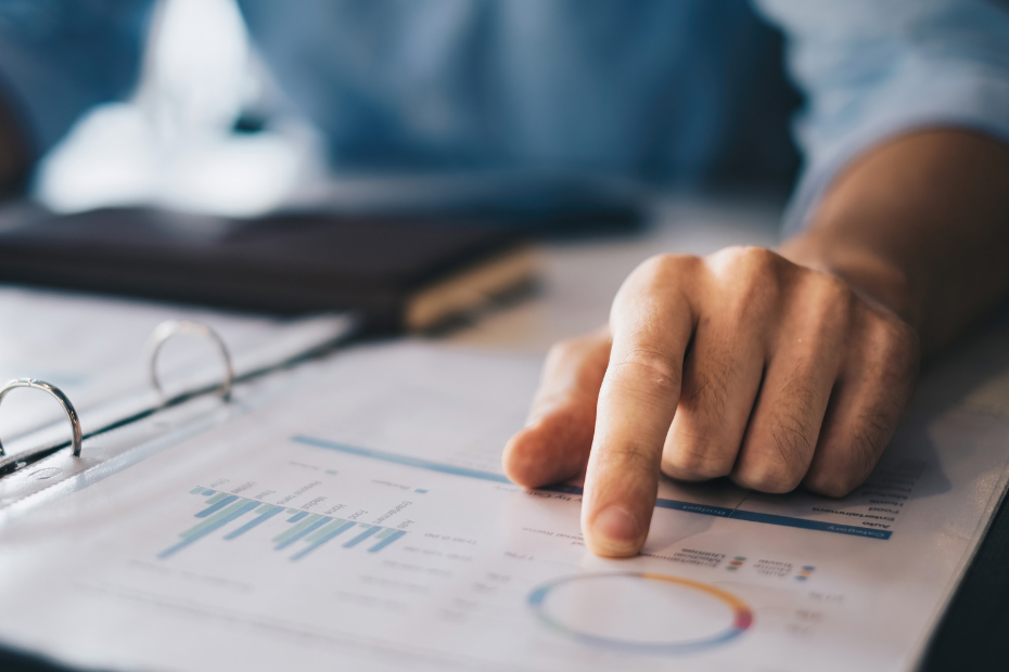 Man out of image at a desk with hand pointing to a pie chart