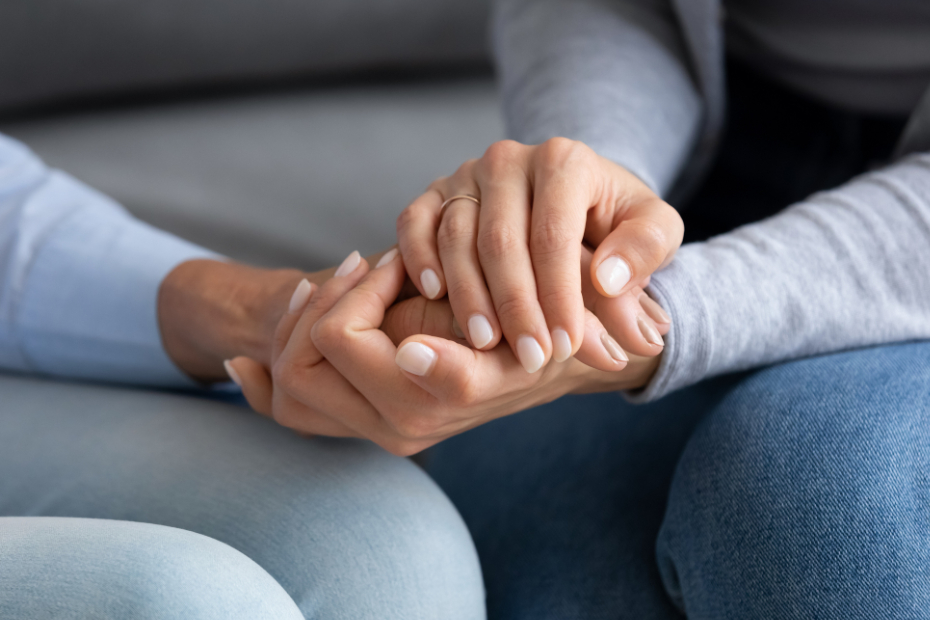 Two people holding hands in a comforting way