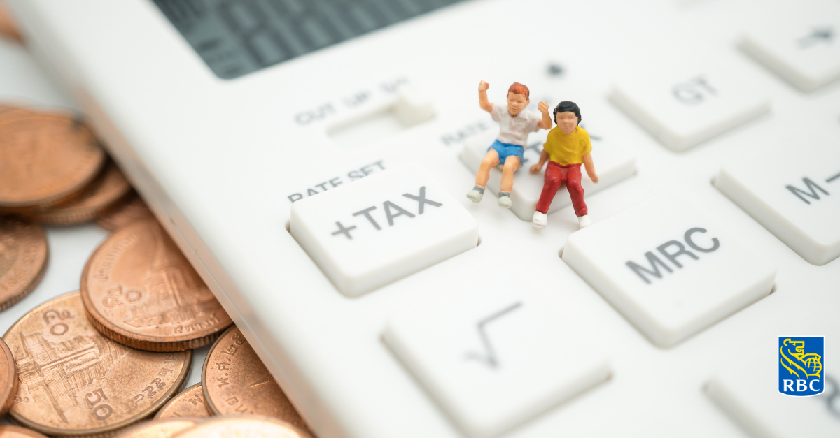 Miniature figures of two children sitting on a life-sized calculator.