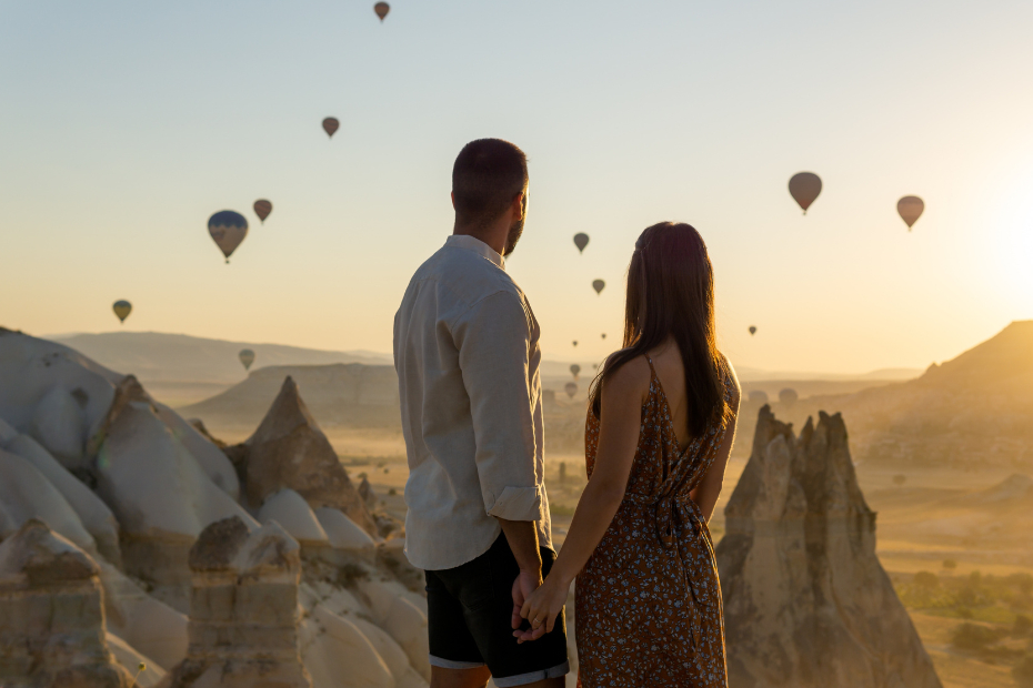 Young Couple holding hands looking at the sun setting over the mountains