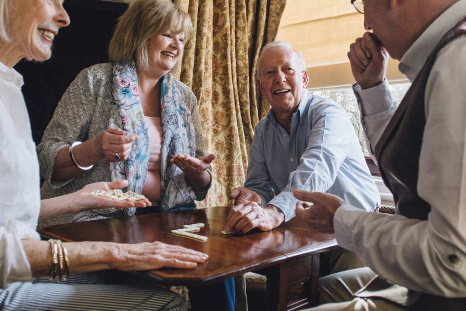 Group of happy seniors around a table playing scrabble