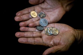 A few coins in the hands of an aging woman.