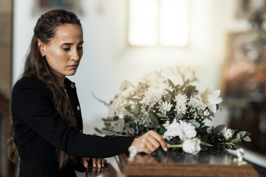 Woman with flower on coffin after loss of a loved one