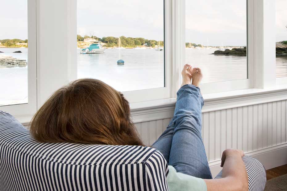 A woman relaxing in a recliner looking out over a lake in her U.S. home