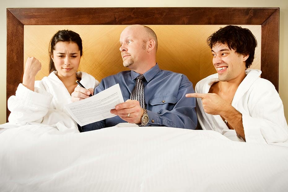 A couple signing legal papers while sitting in their bed.