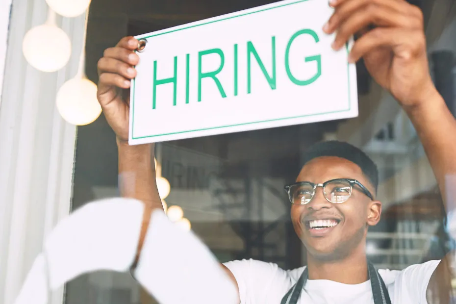 Man putting up Hiring sign on window