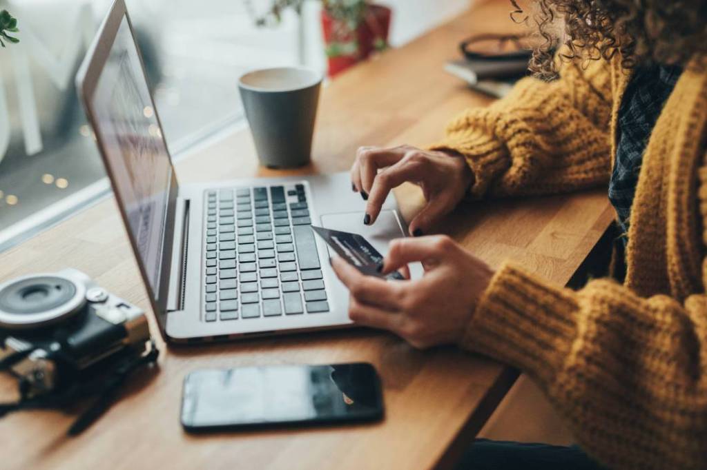 Girl sitting with a card making a payment on her laptop