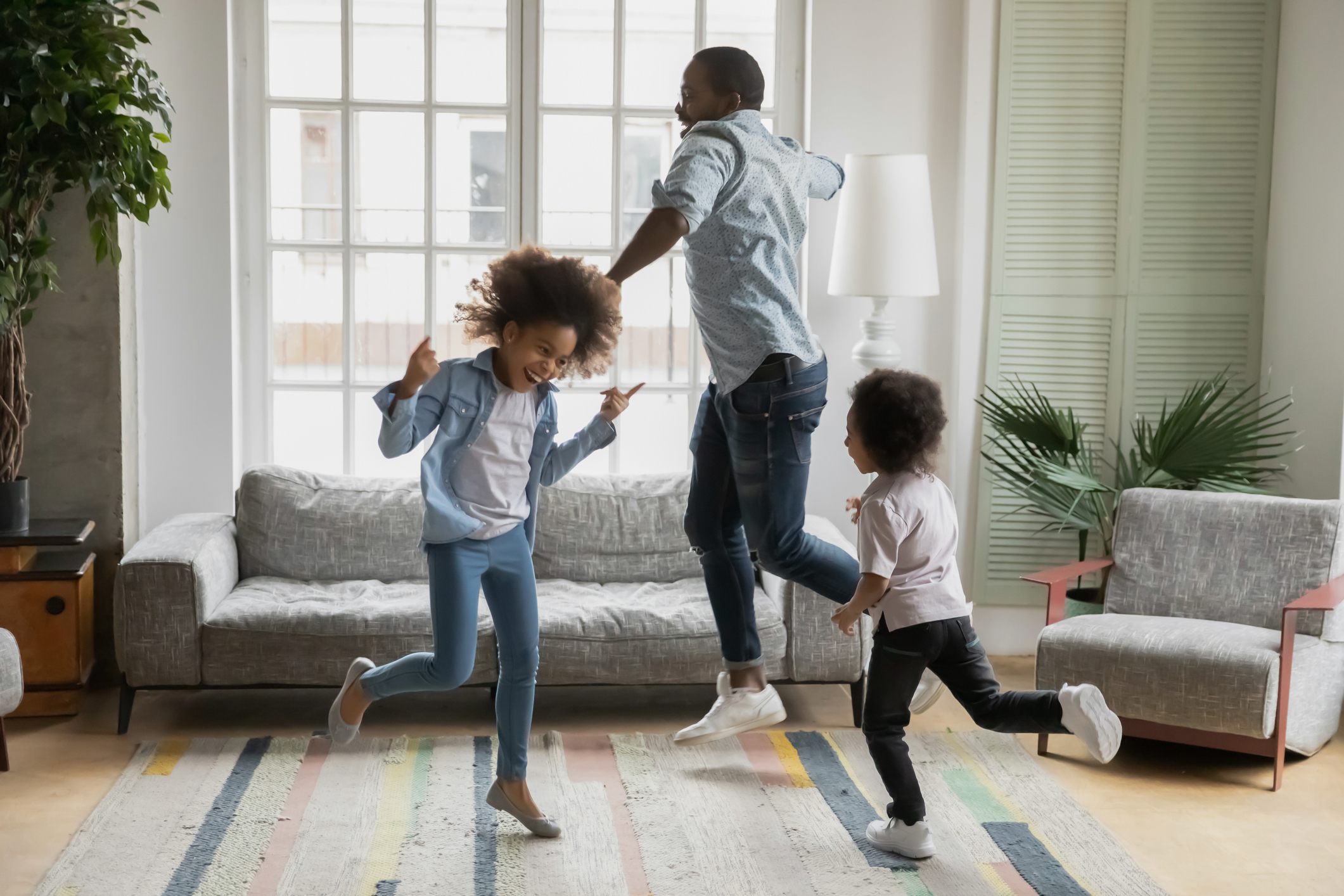 Active african funny dad little son and crazy daughter heavy metal or rock and roll lovers dancing in cozy living room relish life fooling around listening cool music scream with joy enjoy party hard