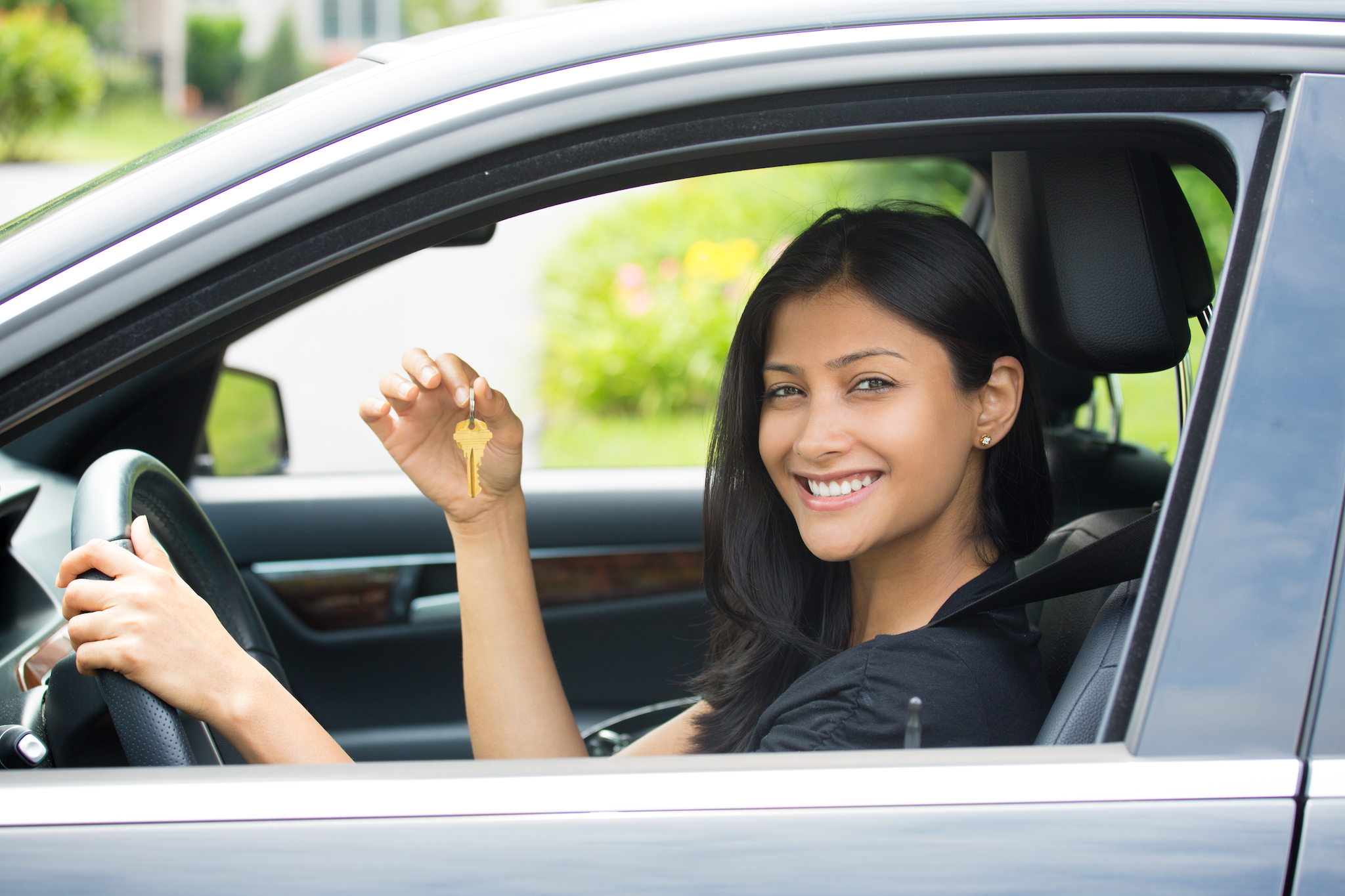 Closeup portrait, young cheerful, joyful, smiling, gorgeous woman holding up keys to her first new car.