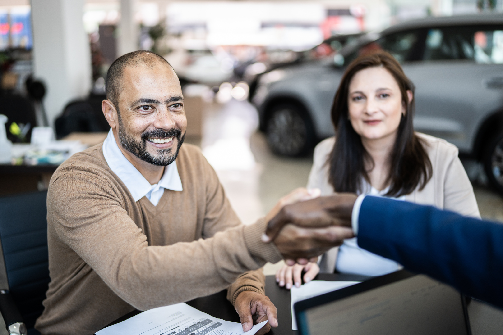 Customer shaking hands with car salesman buying a car