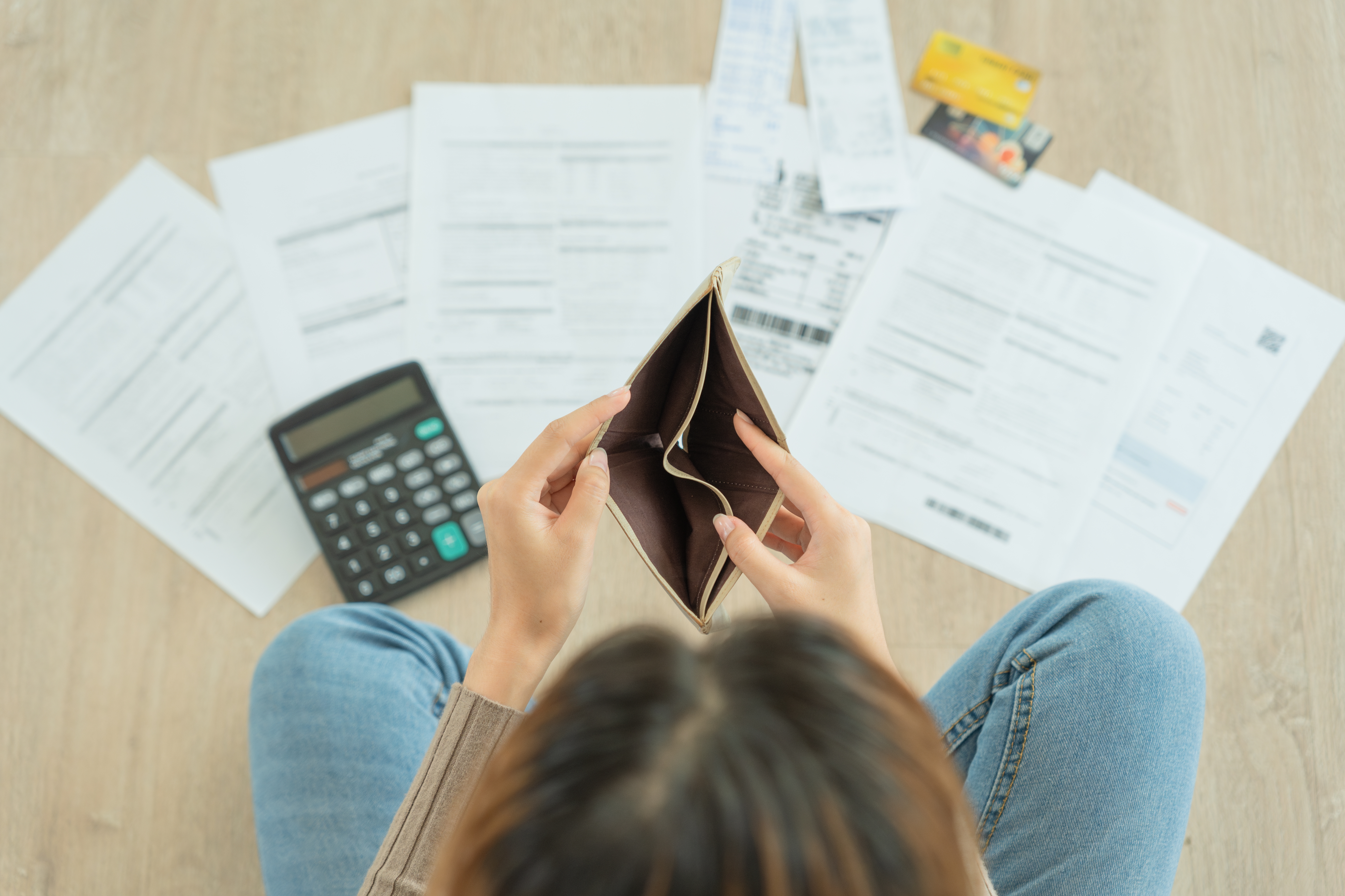 Woman overlooking bills and an empty wallet.