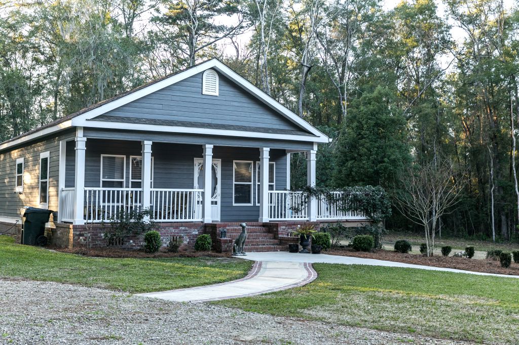 Small blue gray mobile home with a front yard
