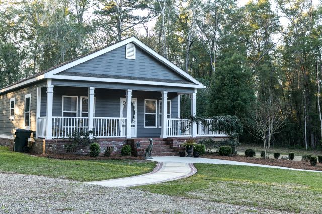 Small blue gray mobile home with a front yard