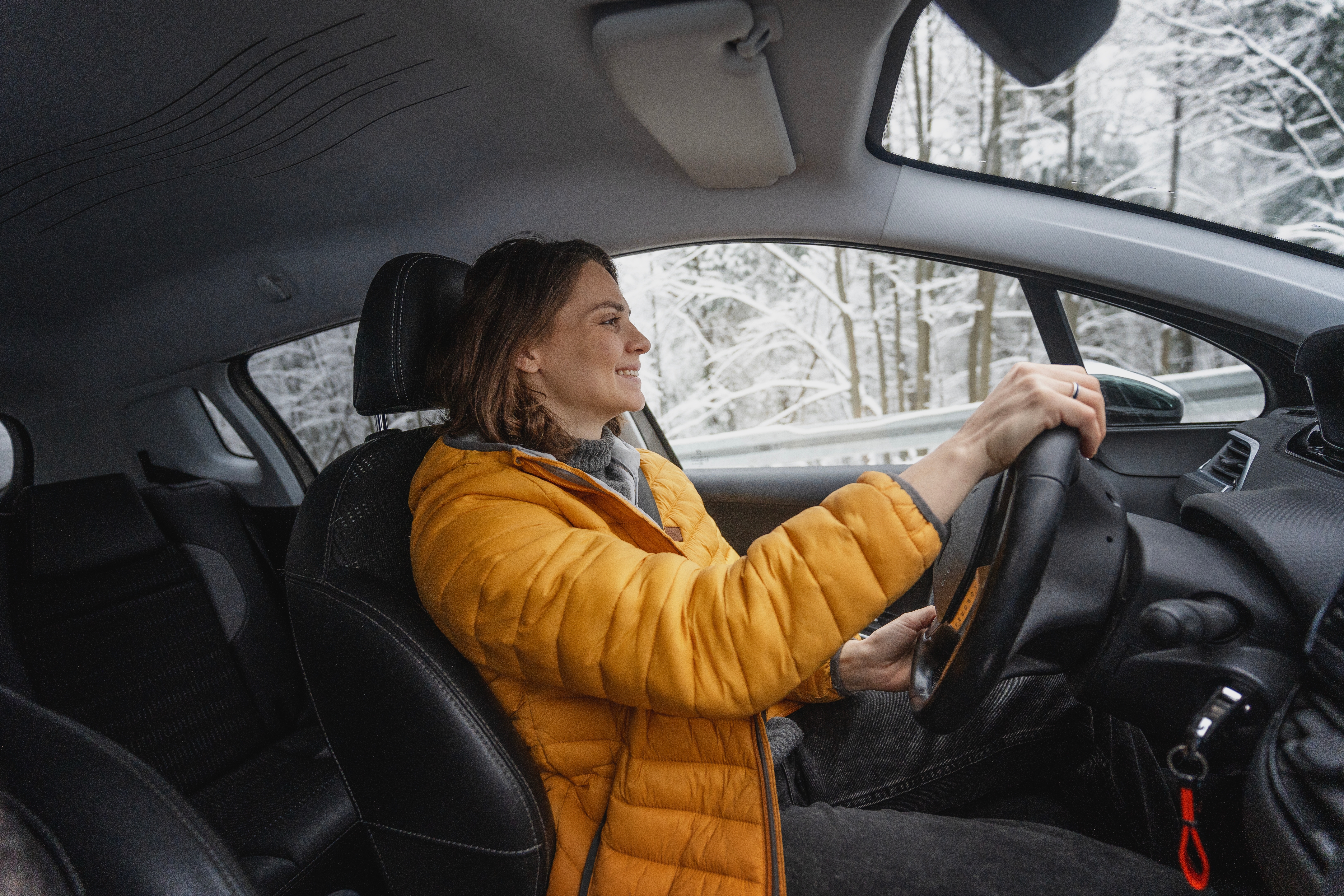 Young happy woman driving her car in the winter