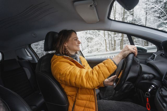 Young happy woman driving her car in the winter