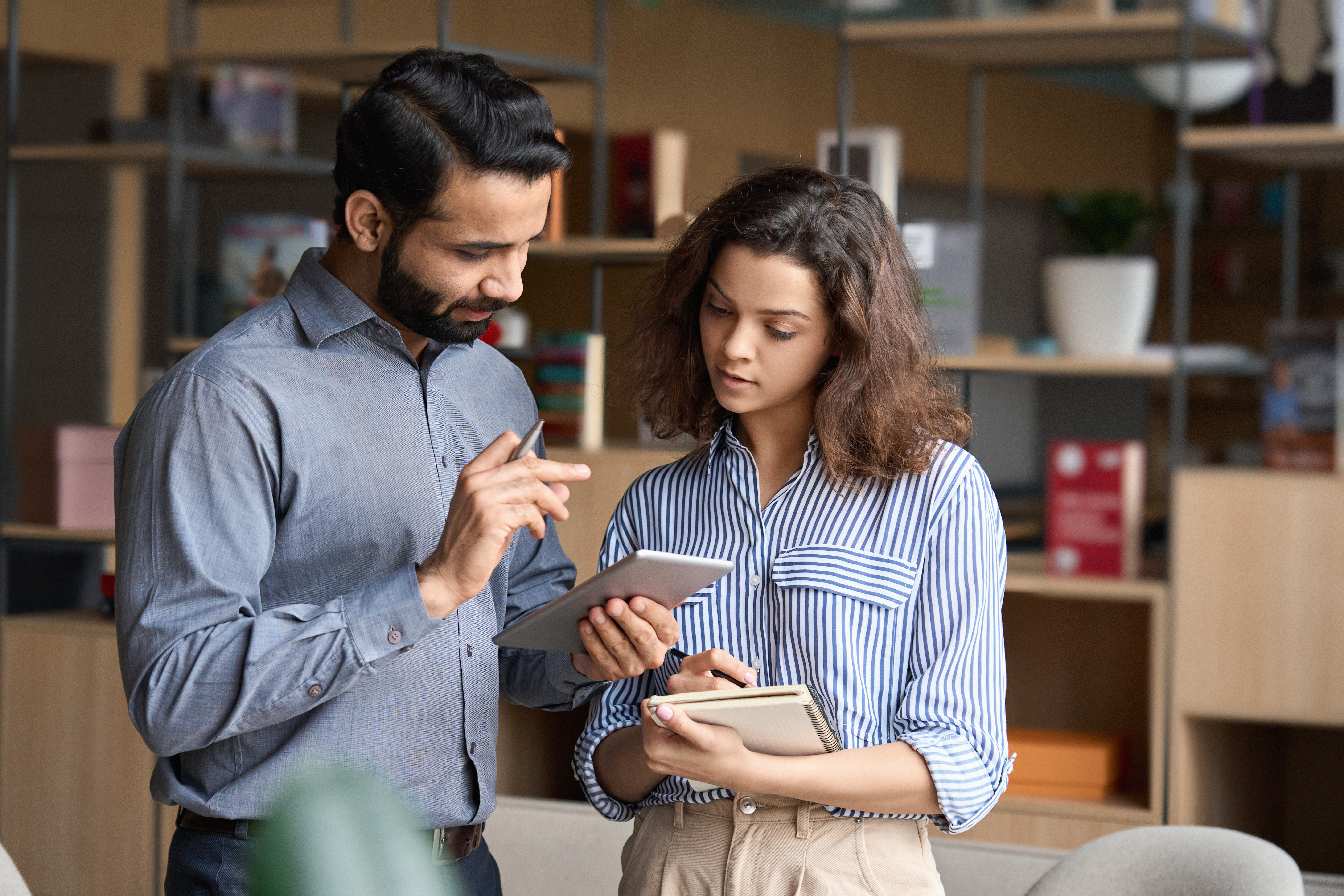 A manager holding a digital tablet and having a discussion with employee