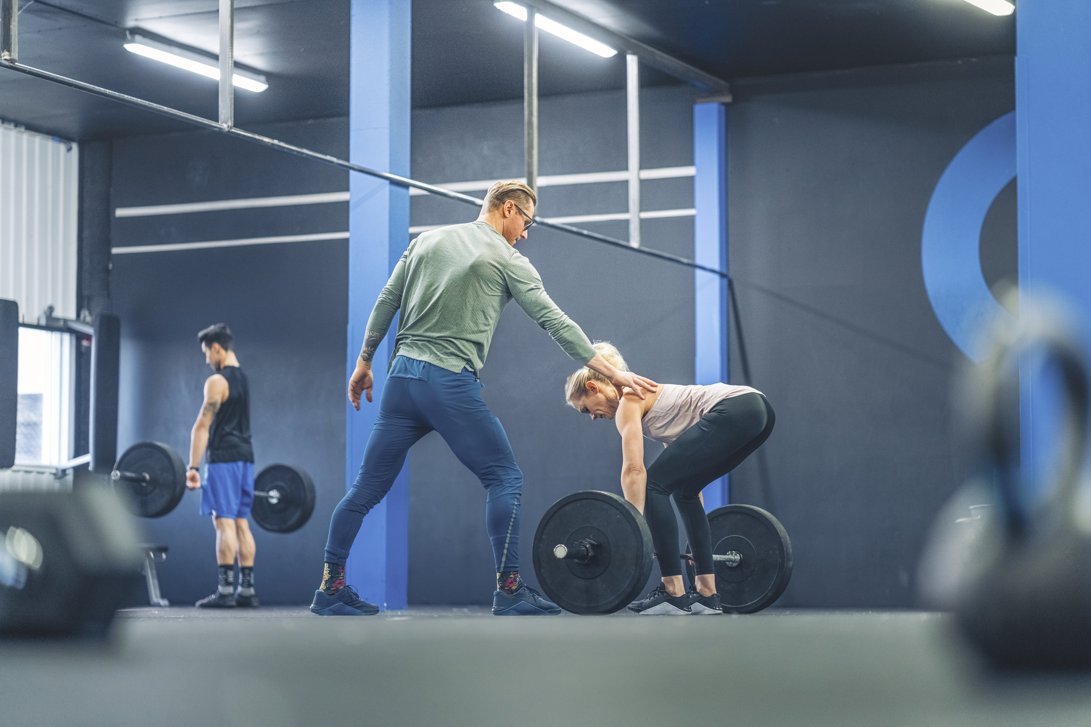 Woman and trainer lifting weights in a gym