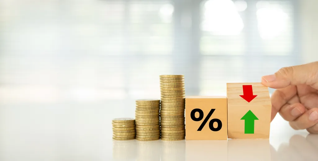 Stack of coins next to toy percentage sign.