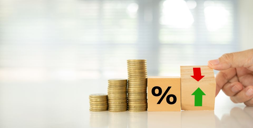 Stack of coins next to toy percentage sign.