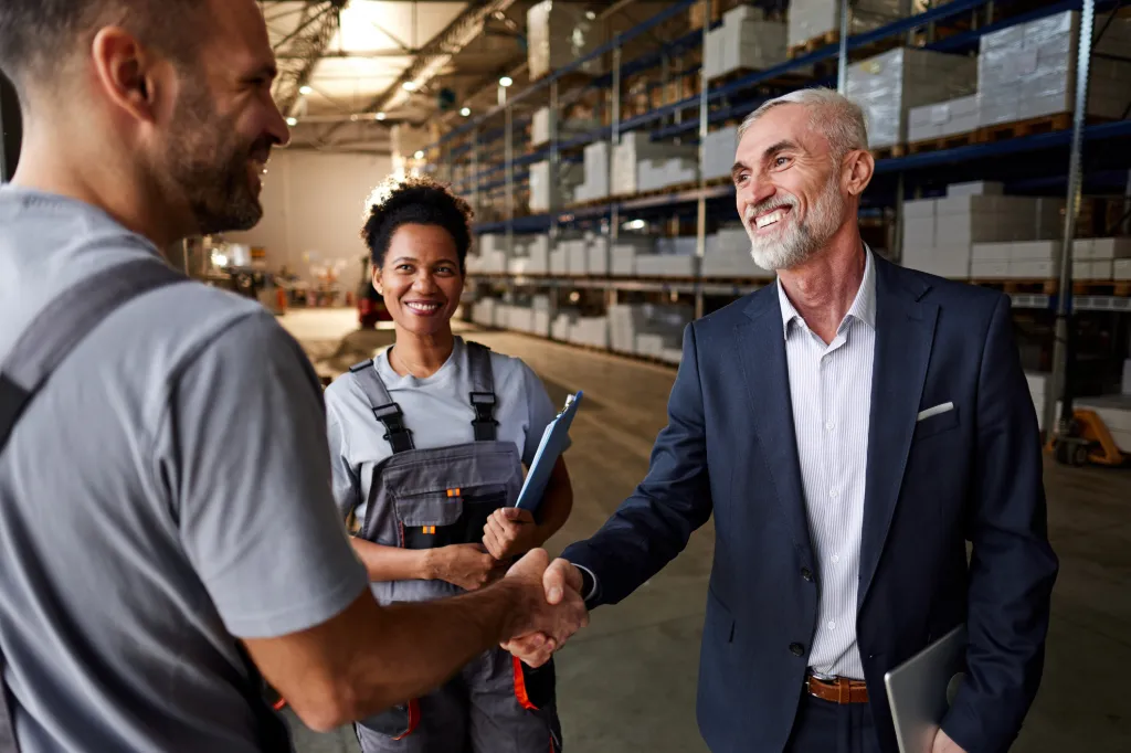 A group of people shaking hands with another in a factory.