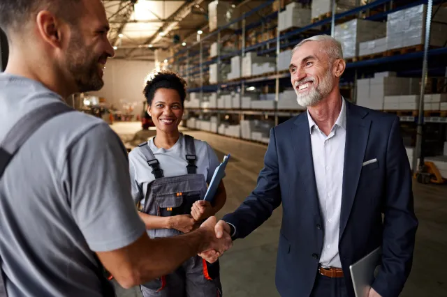 A group of people shaking hands with another in a factory.