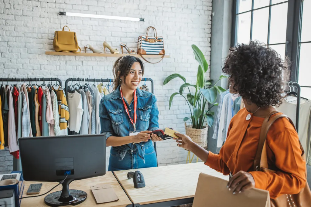 Customer paying with POS terminal at clothing store.