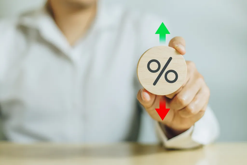 A hand holds a disc with a percentage symbol on it, and upward and downward arrows over and below the disc to reflect the rate announcement on September 17, 2025.