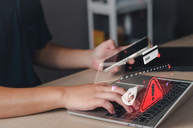 Person typing on computer and phone. Overlay of 3D cyber security illustrations.
