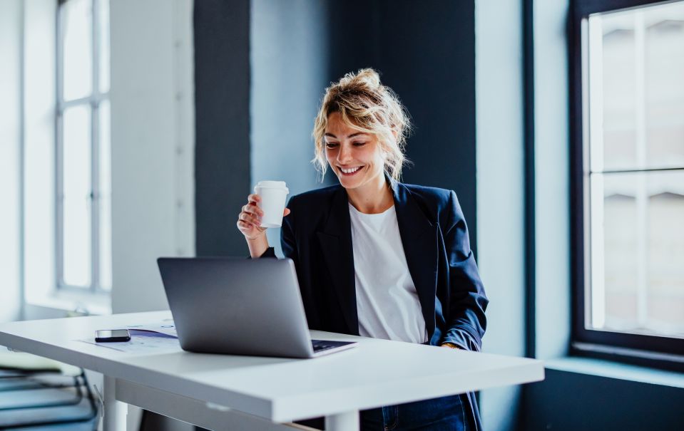 Image of a woman enjoying coffee while working with her laptop