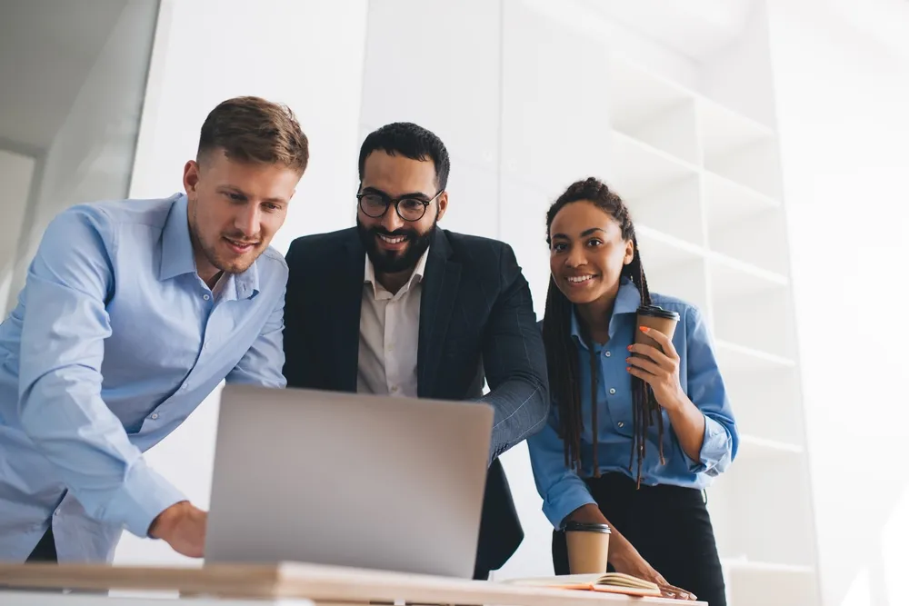 Three colleagues looking at a computer.
