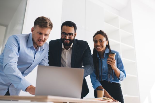 Three colleagues looking at a computer.